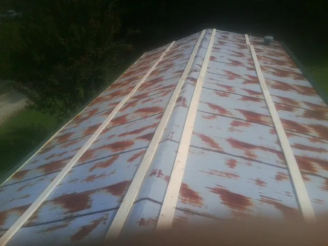 Rusted metal roof panels with new wood purlins before replacement — Storm Damage Roof Repair in Laingsburg by Roofing Brothers