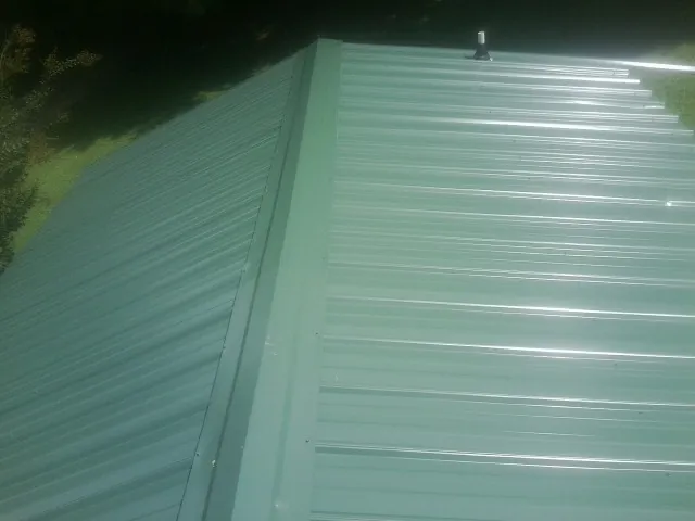 New green metal panels meeting at the ridge of a roof — Flat Roof Repair work by our crew in Laingsburg