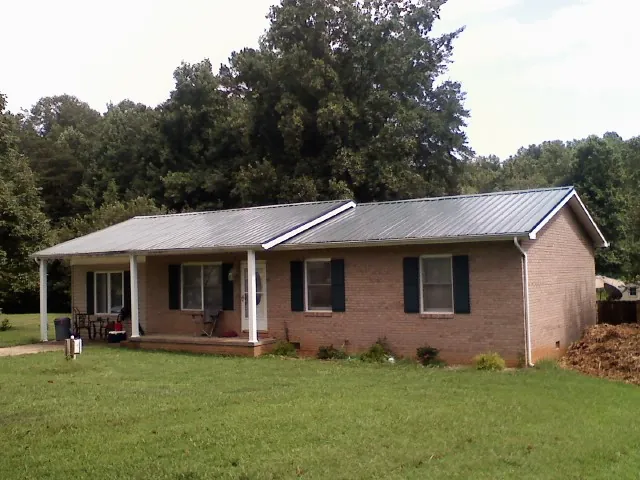 Gray metal roof on a brick ranch house with a side carport in Laingsburg