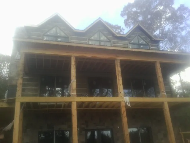 Dormers and porch framing on a large log home under construction — Roof Coating work by our crew in Laingsburg